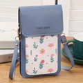 Blue mini crossbody phone bag with floral pocket and adjustable strap on a wooden desk - Blue