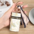 Minibolsa cilíndrica de cuero crema con bordado floral y detalle de pañuelo - Verde claro