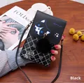 Detalle de bolso negro para móvil con diseño de husky y pompón en mesa de madera - Negro