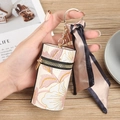 Estuche cilíndrico para labiales con bordado floral, llavero dorado y cinta de seda - Rosa