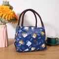 Isolierte Kühltasche in Marineblau mit Katzenmuster auf einem Holztisch mit Blumen - Blaue Kleine Katze