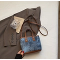 Dettaglio borsa a secchiello in denim vintage con manici in pelle marrone e borchie dorate - Blu