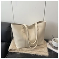 Close-up of cream white leather tote bag on plush scarf with office accessories - White