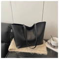 Detail of a black large capacity leather tote bag placed on a soft plush texture - Black