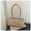 Détail du sac baguette beige avec boucle mors argentée sur un tapis en cuir - Kaki