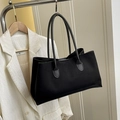 Minimalist black rectangular tote bag in matte finish styled with a cream blazer - Black