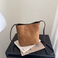 Secchiello chic in camoscio marrone con tracolla in pelle su riviste, stile minimalista autunno - Cuoio