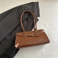 Sac sous le bras marron vintage avec boucle métal sur costume noir et tissu beige - Fauve