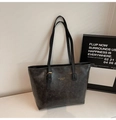 Dettaglio della borsa tote vintage in pelle nera con fibbia dorata e scritte impresse - Nero