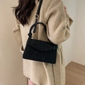 Detail of black corduroy crossbody bag with round handle worn with a beige coat - Black