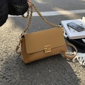 Khakifarbene Umhängetasche aus Leder mit goldener Schnalle und Kette auf Karoteppich - Braun