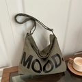 Borsa a tracolla in tela verde militare con scritta MOOD su tavolino di legno - Verde