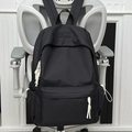 Black minimalist backpack with white cord zipper pulls and side pockets on a chair - Black (No Pendant)
