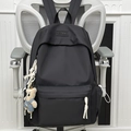 Minimalist black backpack with teddy bear pendant and woven zipper pull on a chair - Black (With Pendant)