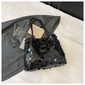 Dettaglio della borsa tote con paillettes nere e manici intrecciati su tessuto bianco - Nero
