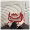 Close-up of red leather shoulder bag with cream pleated flap and heart metal pendant - Red