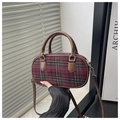 Detail van geruite crossbodytas met rood-groene plaidstof en bruin lederen handvat - Rood