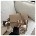 Detail of beige crossbody bag with gold F logo and decorative woven strap on white sofa - Khaki