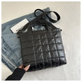 Dettaglio della borsa tote trapuntata nera con trama piumino e doppie tracolle su denim - Nero