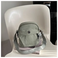 Close-up of sage green nylon crossbody bag with metallic logo and textured fabric - Green