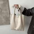 Minimalist cream suede tote bag with flap closure shown in a handheld lifestyle view - White