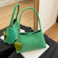 Green suede shoulder bag with long top handles and decorative charm in a mirror display - Green