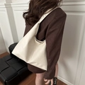 Sac fourre-tout minimaliste crème à texture cuir et grande capacité porté par un mannequin - Blanc Cassé