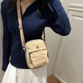 Khaki nylon crossbodytas met verstelbare riem en metalen logo gedragen door model - Khaki