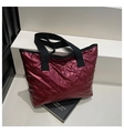 Detail of burgundy quilted tote bag with embossed bow patterns and black web handles - Red