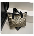 Detailed close-up of champagne gold tote bag with quilted bow texture and black straps - Gold