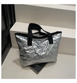 Detail of silver metallic quilted tote bag with embossed bow patterns and black straps - Silver