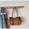 Detalle del bolso tote de ante marrón mate colgado en un gancho de madera con estilo retro - Marrón