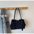 Detalle de bolso tote de ante negro con hebilla metálica en un entorno de estilo minimalista - Negro