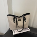 Borsa tote minimalista in tela beige con finiture in pelle nera e manici sul divano - Nero