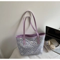 Detalle de bolso tote a cuadros morados con remaches plateados y asas de cuero en mesa - Violeta