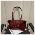 Dettaglio macro della borsa tote in pelle lucida bordeaux con fibbia argentata e cuciture - Rosso