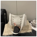 Dettaglio borsa bianca in pelle PU lucida con borchie argentate e tracolla di tendenza - Bianco