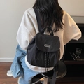 Zaino minimalista in nylon nero con chiusura a patta indossato da una modella - Nero