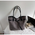 Detail shot of a large grey tote bag featuring black decorative belts and metal hardware - Gray
