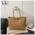 Dettaglio della borsa tote trapuntata color cammello in un ambiente domestico accogliente - Cachi