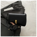 Detalle de un elegante bolso negro con hebilla ovalada de metal dorado brillante - Negro