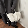 Minimalist white tote bag with lychee texture held by a model in a grey suit - White
