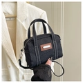 Detail van zwarte denim handtas met witte contraststiksels en zilveren hardware - Zwart