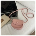 Pink mini crossbody bag in lychee texture on white fabric next to a magazine - Pink