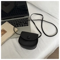 Detail of black litchi pattern leather mini crossbody bag on a textured white fabric - Black