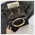 Minimalist black leather handbag with a large polished gold oval metal handle and chain - Black