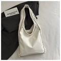 Dettaglio di una borsa Hobo in pelle bianca con rivetti argentati su tracolla minimalista - Bianco