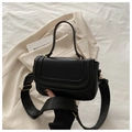 Detail of black smooth PU leather bag with wide strap and gold metal buckle on beige blazer - Black