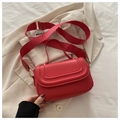 Detail of red square crossbody bag with gold hardware and wide nylon strap on white blazer - Red