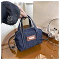 Dettaglio borsa Boston in denim blu scuro con cuciture bianche e finiture in pelle - Blu